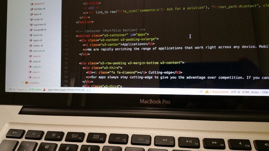 A modern silver laptop with a black keyboard and a large trackpad, positioned on a light wooden desk. The laptop's screen displays lines of colorful programming code on a dark background, indicating a